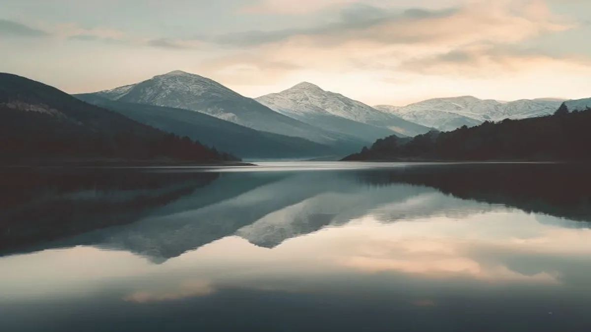 Calm lake with mountain reflection at dawn.