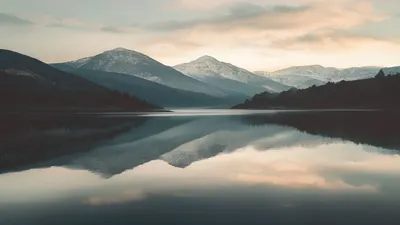 Calm lake with mountain reflection at dawn.
