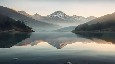 Calm lake with mountain reflection at dawn.