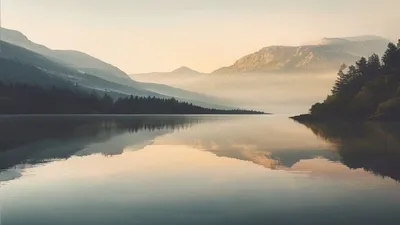 Calm lake with mountain reflection at dawn.