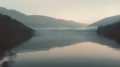 Calm lake with mountain reflection at dawn.