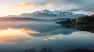 Calm lake with mountain reflection at dawn.