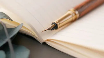 A closeup of a luxurious fountain pen resting on a lined notebook, perfect for writing enthusiasts.