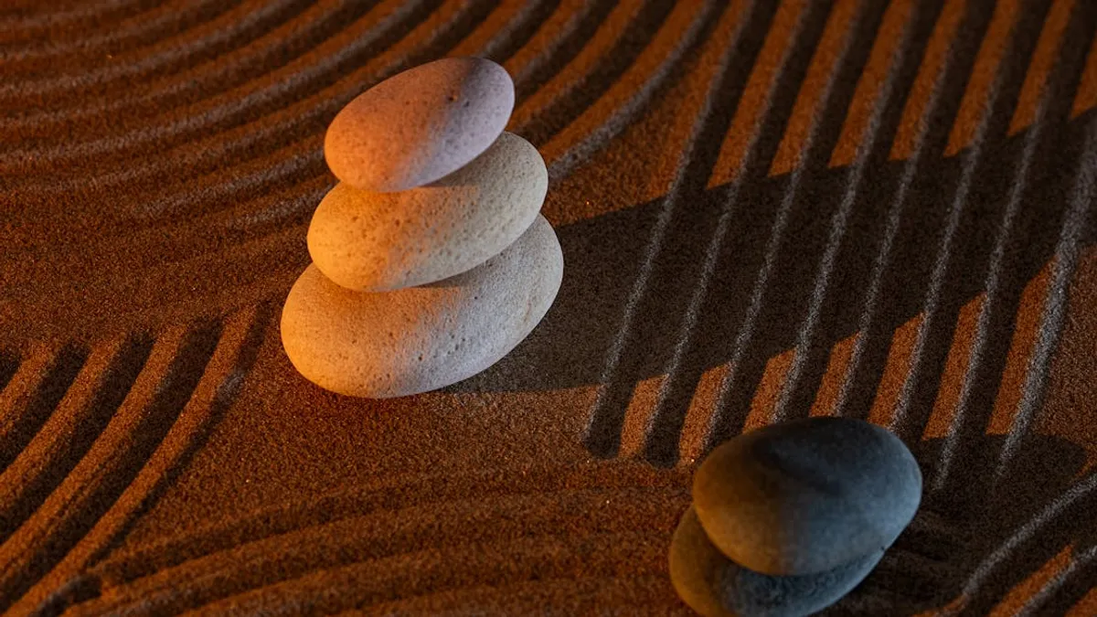 Stacked zen stones on textured sand create a calming and minimalist composition.