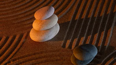 Stacked zen stones on textured sand create a calming and minimalist composition.