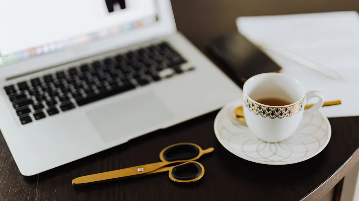 Stylish workspace featuring a laptop, tea cup, and stationery on a wooden table.
