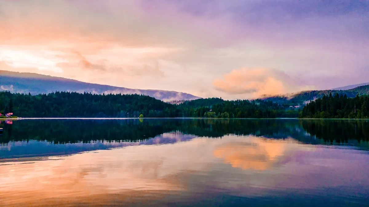 Vibrant sunset over a tranquil lake with mountain reflections in Clearwater, BC.