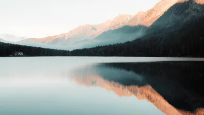 Peaceful morning view of a mountain lake with perfect reflections and misty ambiance.